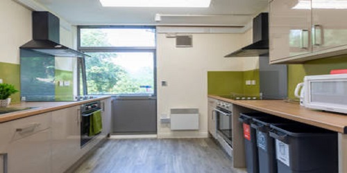 A large kitchen with ovens, hobs and storage on either side of the room.